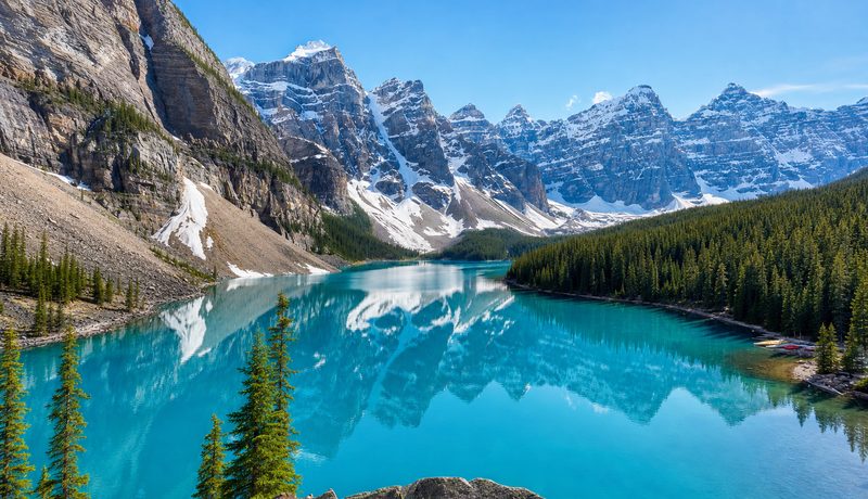 News thumbnail photograph of a turquoise lake, forest, and dramatic snow-covered mountain range.