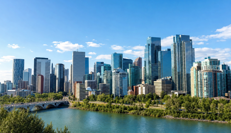 Landscape news thumbnail of a modern city skyline, likely Calgary, with towers and blue sky.